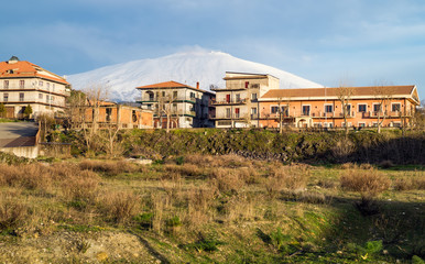 Fototapeta na wymiar Bronte town under the snowy and majestic volcano Etna