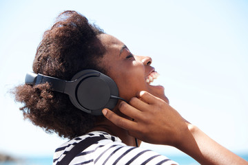 Young african american female listening music on headphone and laughing