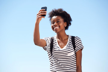 Cheerful young african woman talking selfie outdoors against sky