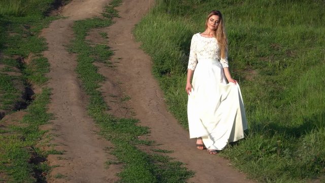 Beautiful young woman in white dress walking on the pathway