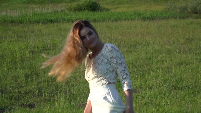 Beautiful young woman playing with hair on the meadow slow motion
