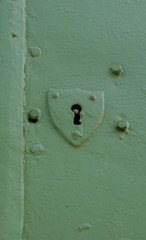 Old and plain shield shaped door key hole on a green door