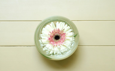 beautyful flower in glass of water on white table, spa, top view
