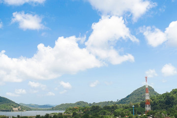 Bright blue sky with mountain view with radio transmission pole or telecommunication tower in a distance.