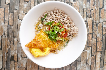 Noodles with minced pork in white bowl on wood table. Top view. Thailand street food