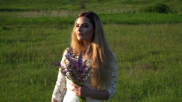Beautiful young woman walking on the meadow with flowers closeup