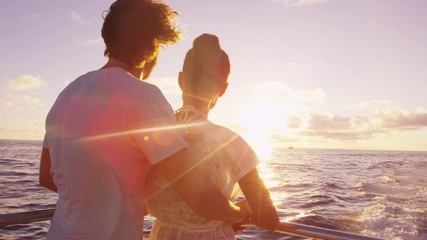 Cruise ship vacation couple enjoying sunset view sailing on small cruise boat at sea. Romantic couple on honeymoon travel at sea looking at sunset. RED EPIC SLOW MOTION. - Powered by Adobe