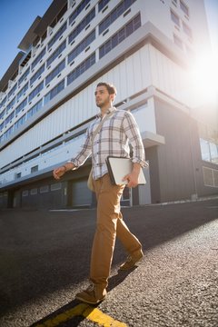 Man holding laptop while walking on city street