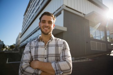 Smiling man with arms crossed standing by building in city