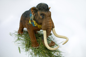 Toy mammoth on white background on the grass