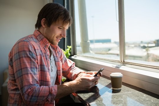 Businessman using phone while sitting by window