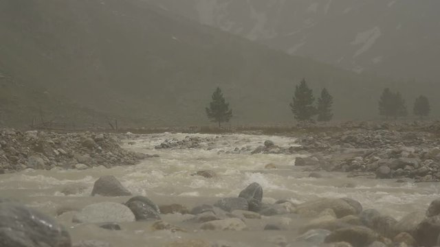 Storm with hail in slow motion over mountain river