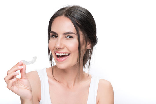 Cheerful young woman showing clear aligner