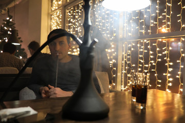 Obraz na płótnie Canvas man smoking pipe of hookah in night cafe