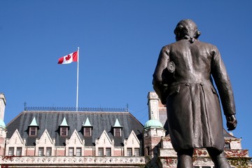 Statue of Captain James Cook and the canadian flag flying in Victoria, British Columbia, Canada