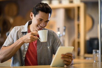 Man using digital tablet while having coffee in restaurant