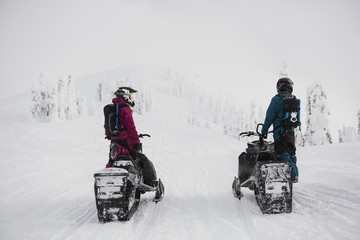 Couple riding snowmobile in snowy alps