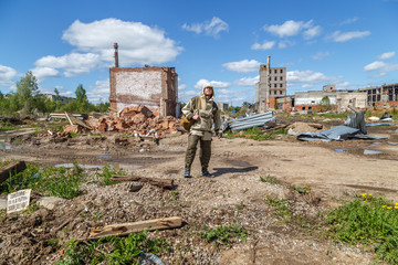 A man with a backpack in military uniform on the background of destroyed buildings