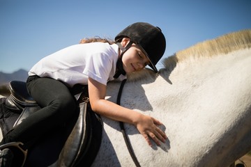 Obraz premium Smiling girl embracing the white horse in the ranch