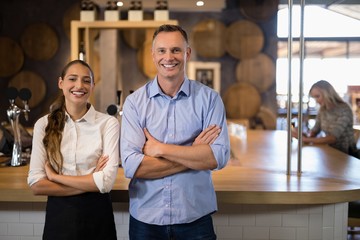 Couple standing with arms crossed near bar counter