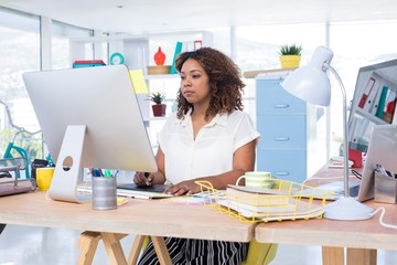 Female executive working over graphic tablet at her desk