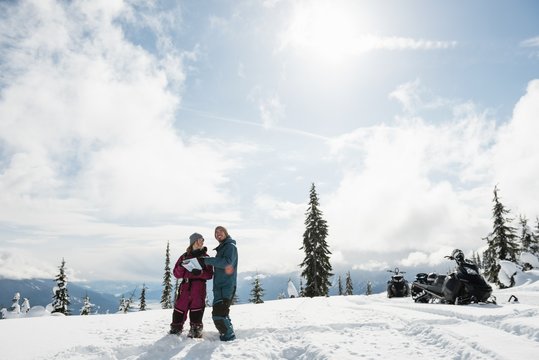 Couple interacting over map in snowy alps