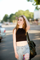 Obraz premium A beautiful young stylishly dressed girl walks in the city, drinks juice or a cocktail, eats sweets, makes selfie on a mobile phone