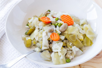 Dish with cooked mixed vegetables on wooden table, Spanish cuisine (Menestra de Verduras). Diet and healthy food concept.