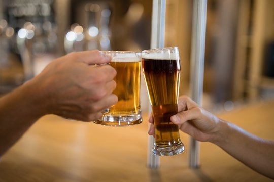 Couple toasting glass of beer at bar counter
