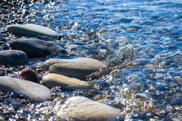 sea pebble beach with multicoloured stones, waves with foam