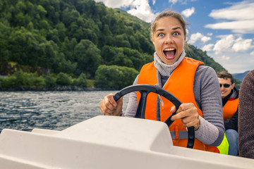 Portrait of young and attractive woman close up driving the motorboat, Norway. She is enjoying the sunny day.