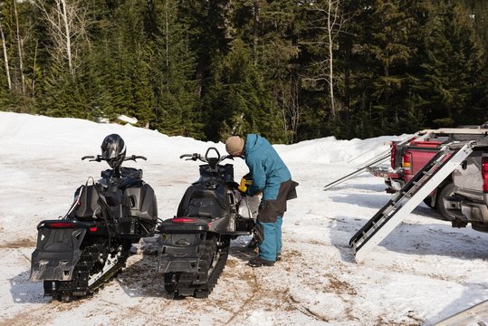 Man filling gas tank of snowmobile