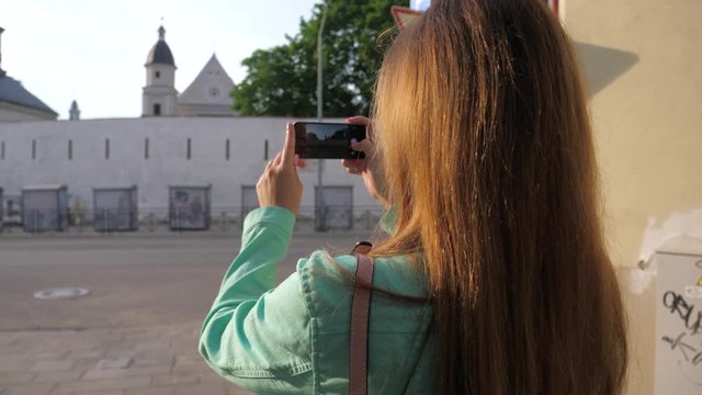 Woman traveler enthusiastically taking pictures on a smartphone.