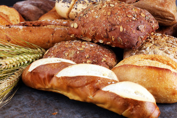 Different kinds of bread and bread rolls on board from above. Kitchen or bakery poster design.