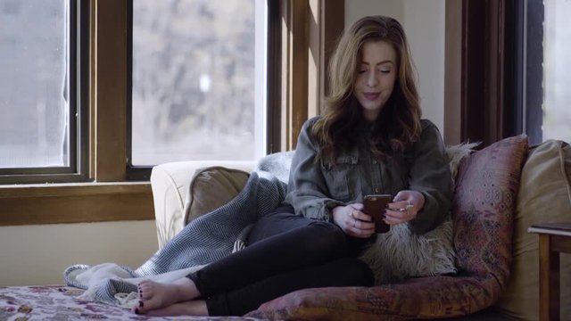 Young Woman Relaxes And Uses Her Smartphone