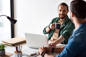 Merry smiling worker sitting in office