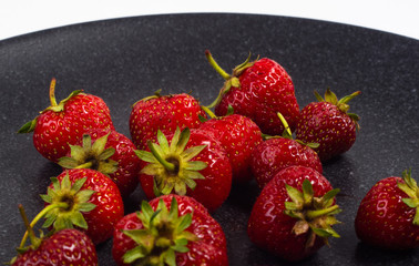 fresh ripe strawberries on black ceramic plate
