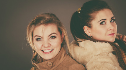 Two women wearing light brown coats