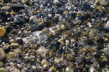 sea pebble beach with multicoloured stones, waves with foam
