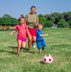 Mom and her two sons play football in the lawn