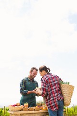 Woman buying organic vegetables from man against sky