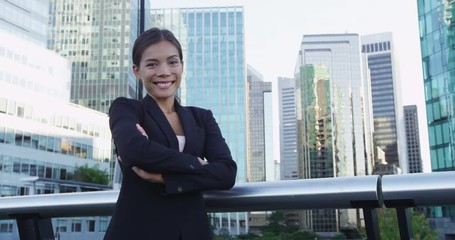 Asian Business woman portrait of young female urban professional businesswoman in suit with arms crossed in Downtown Vancouver, Canada. Confident successful multicultural Asian / Caucasian woman