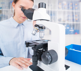 young woman scientific / female student researcher looking microscope  in a laboratory.