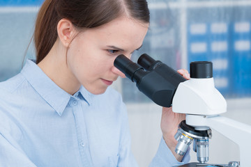 young woman scientific / female student researcher looking microscope  in a laboratory.