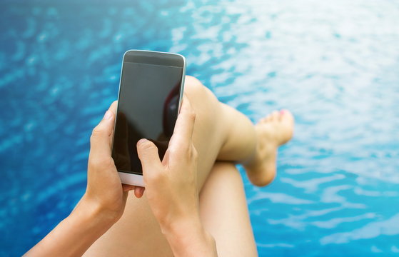 Girl using phone by the swimming pool