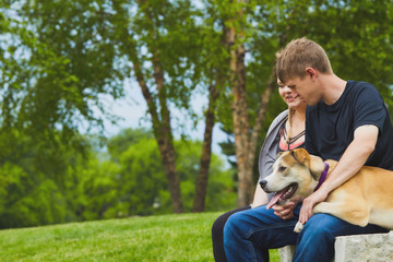 Smiling couple resting on stone with their dog