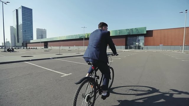 Businessman in a suit with bicycle leaving office at end of day.