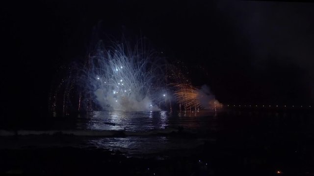 Fireworks blowing in night sky and reflecting in water