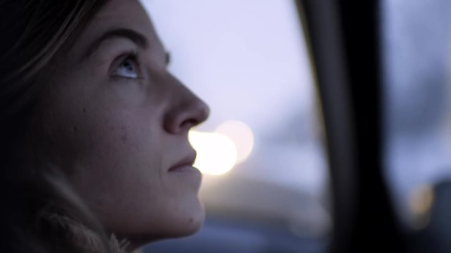 Closeup Profile Of Young Woman Looking Out Car Window On A Snowy Winter Night