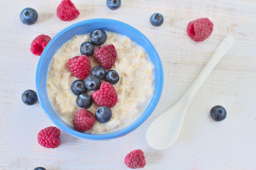 Oatmeal porridge with blueberries and raspberries in bowl - healthy rustic breakfast for kids